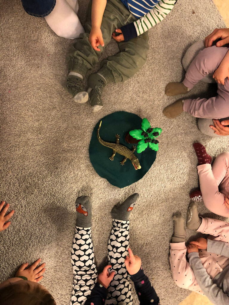 Barn sitter i ring och sjunger om dinosaurie