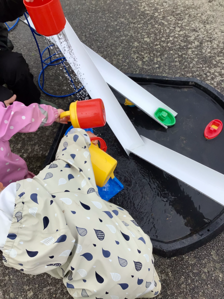 Vattenlek med hinkar och leksaksbåtar utomhus